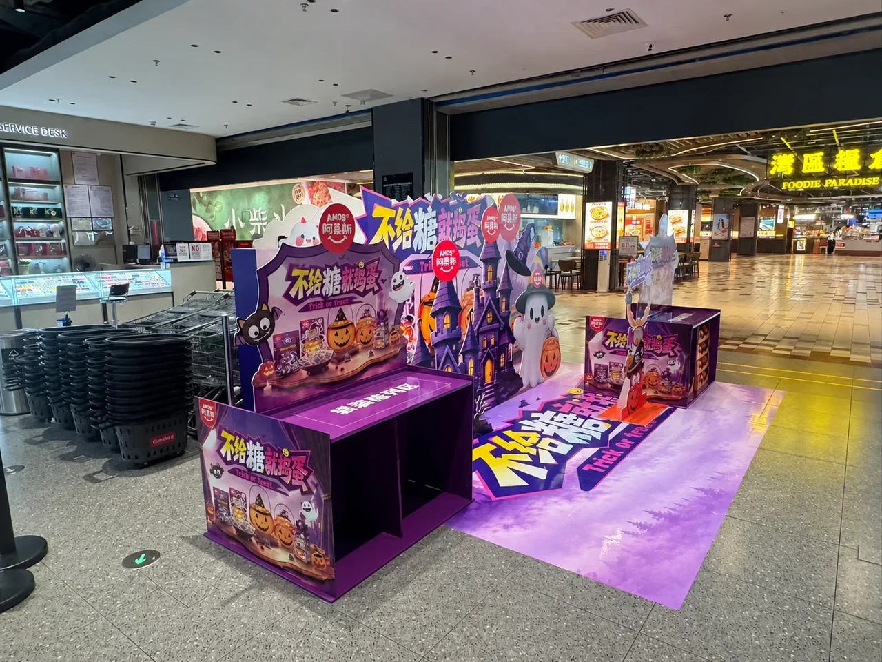 Front view of a Halloween promotion zone at a supermarket entrance with die-cut themed backdrops, display units and a purple floor graphic